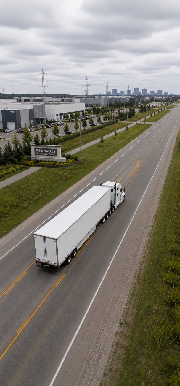 Camion de transport fermé blanc sur une autoroute canadienne près d’un parc industriel